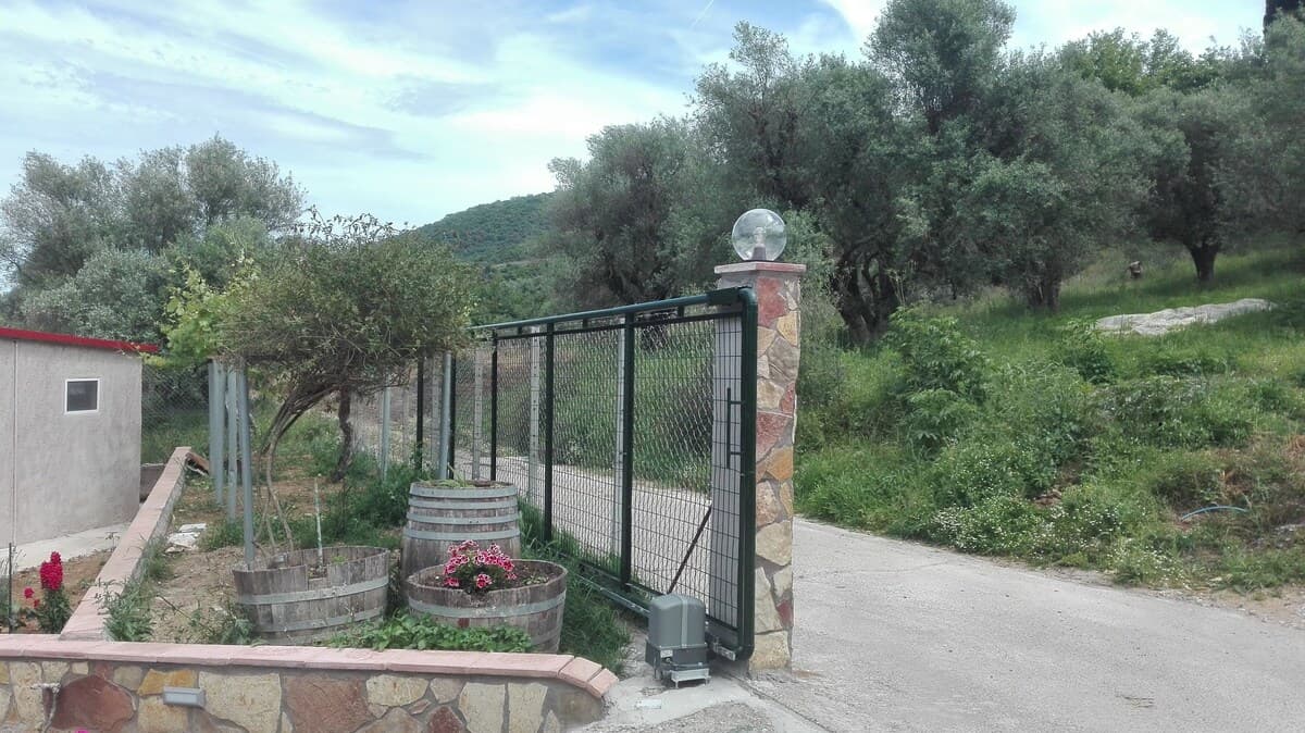 Property entrance with stone pillars and olive trees