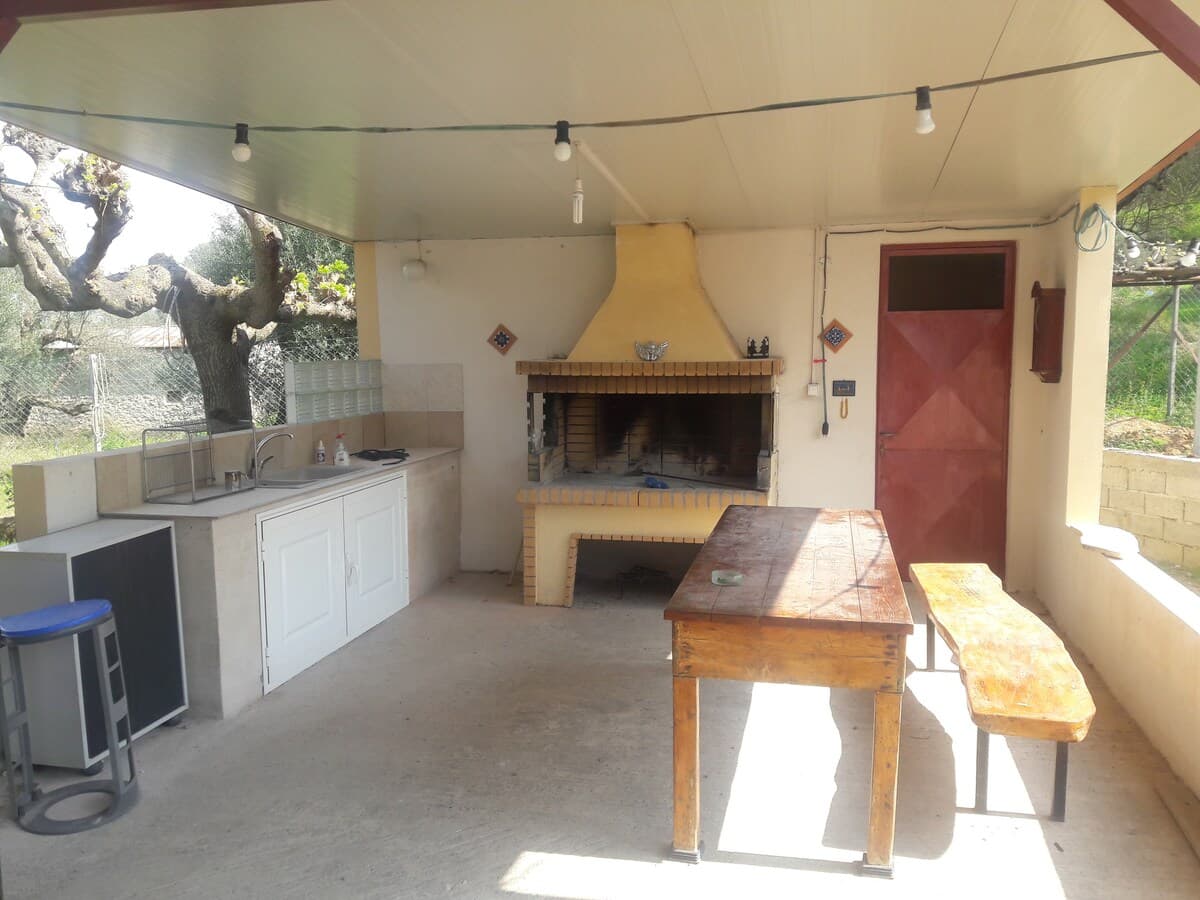 Outdoor BBQ kitchen with stone fireplace and string lights