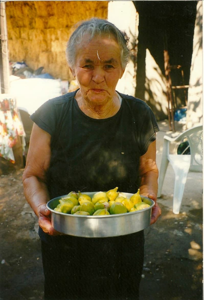 Oma Ourania in Lysimachia \u2014 the woman the kalyva is named after, holding fresh figs from the village
